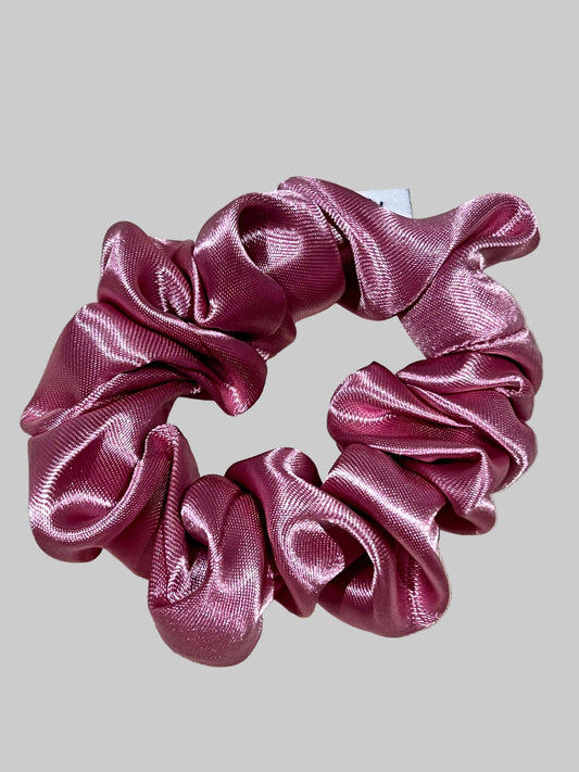 Pink satin scrunchie on a light beige background