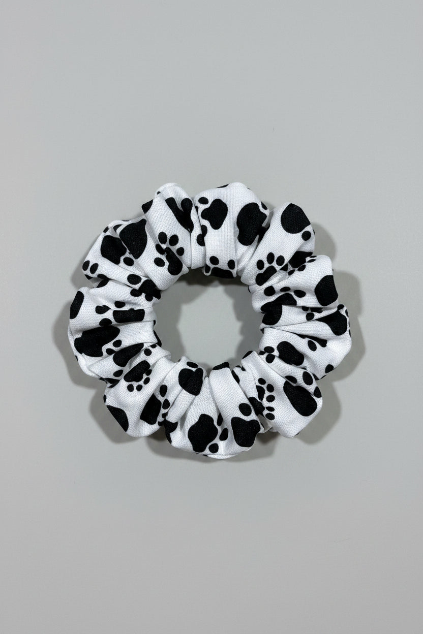 Scrunchie with black paw prints on a beige fabric background