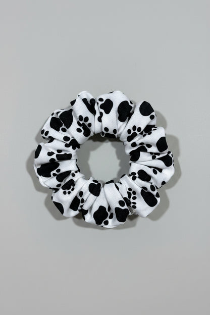 Scrunchie with black paw prints on a beige fabric background