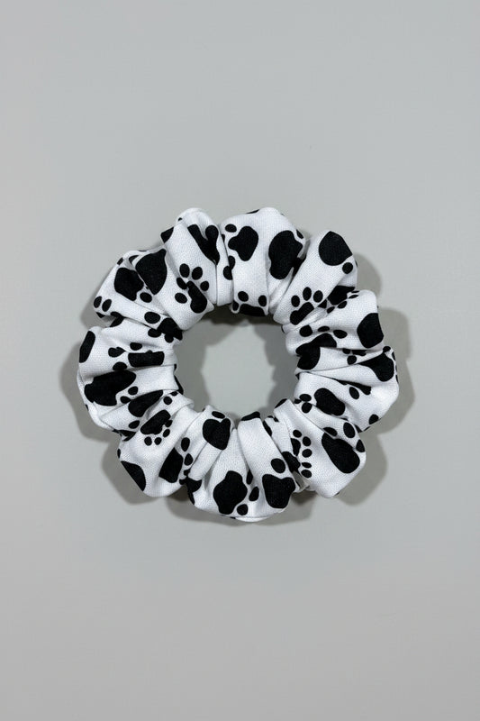 Scrunchie with black paw prints on a beige fabric background